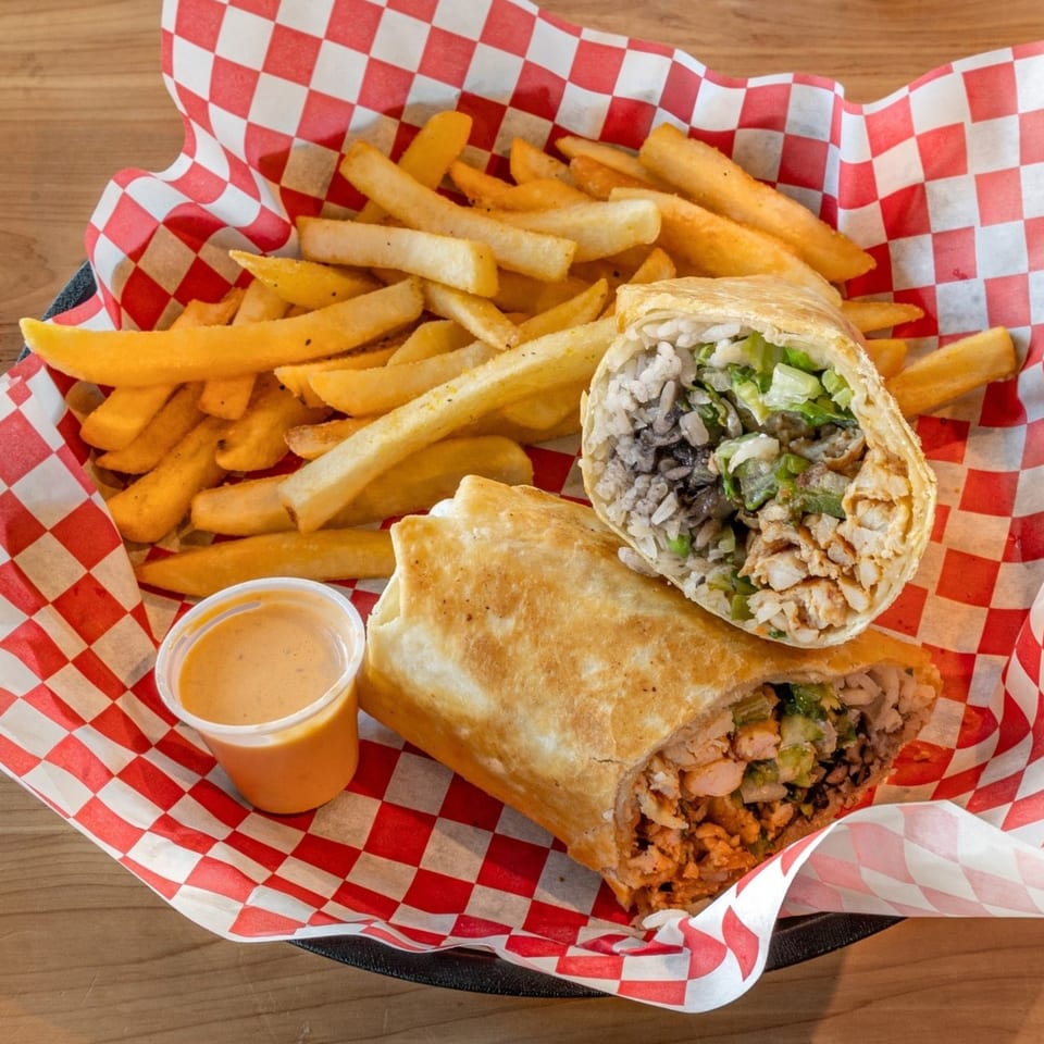 Two El Rey Tacos & Beer burritos, one cut in half, with fries and dipping sauce in a basket.